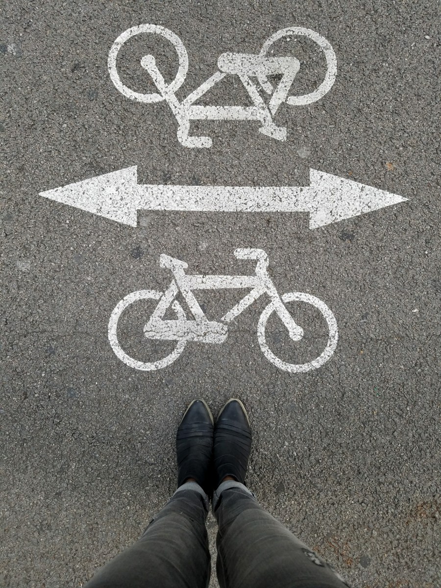 Legs and boots standing next to bicycle symbols on the pavement