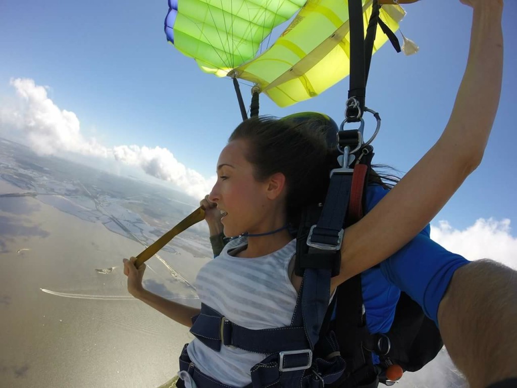 Woman attached to parachute looking down from the air