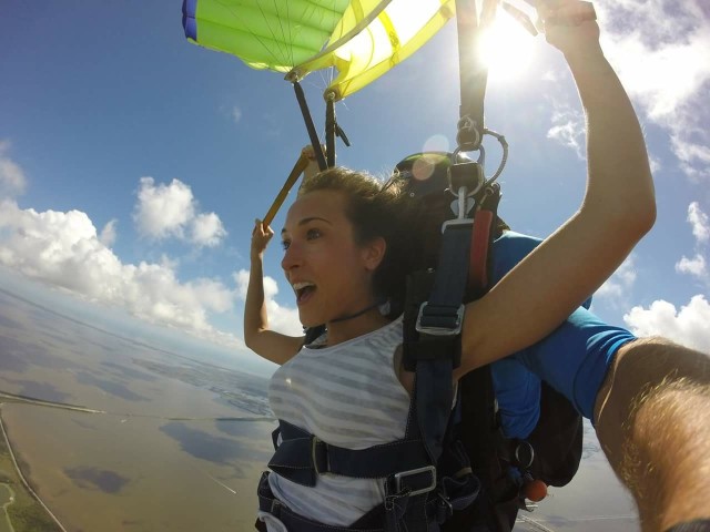 Woman attached to parachute, excited about skydiving