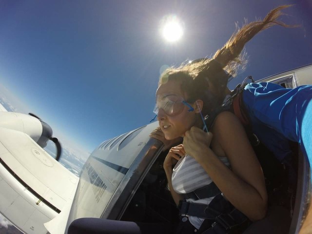 Woman in the doorway of a plane, about to go skydiving