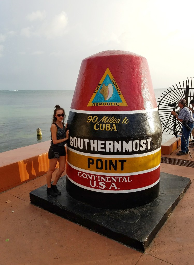 Woman standing next to Southernmost Point Continental USA point in Key West Florida