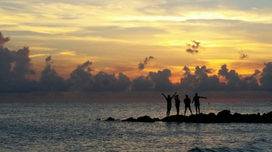 Silhouette of four women on a jetty on the beach