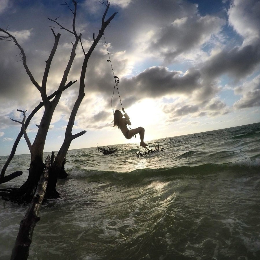 Woman swinging on a swing over the ocean