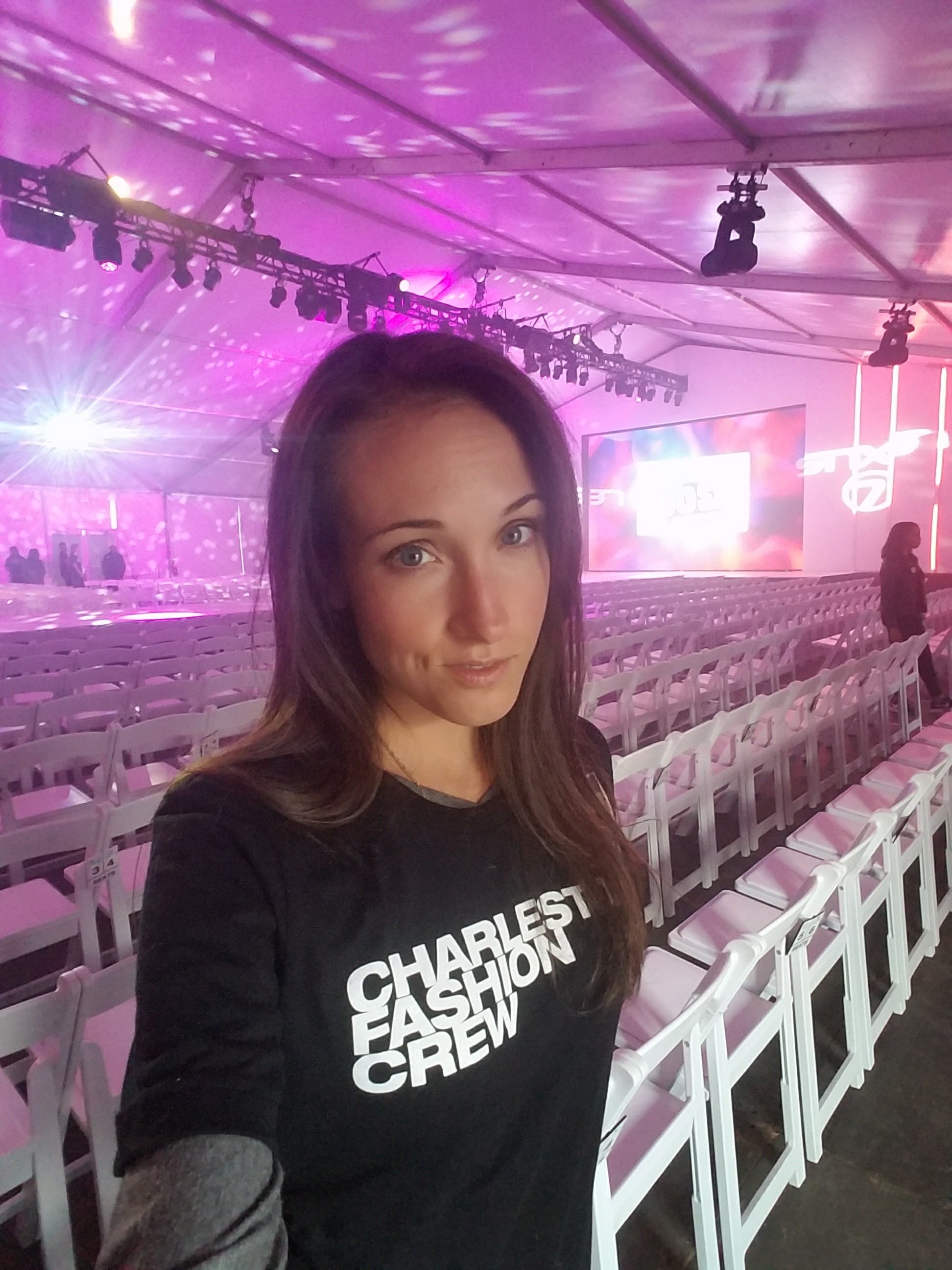 Woman wearing "Charleston Fashion Week" t-shirt with rows of chairs