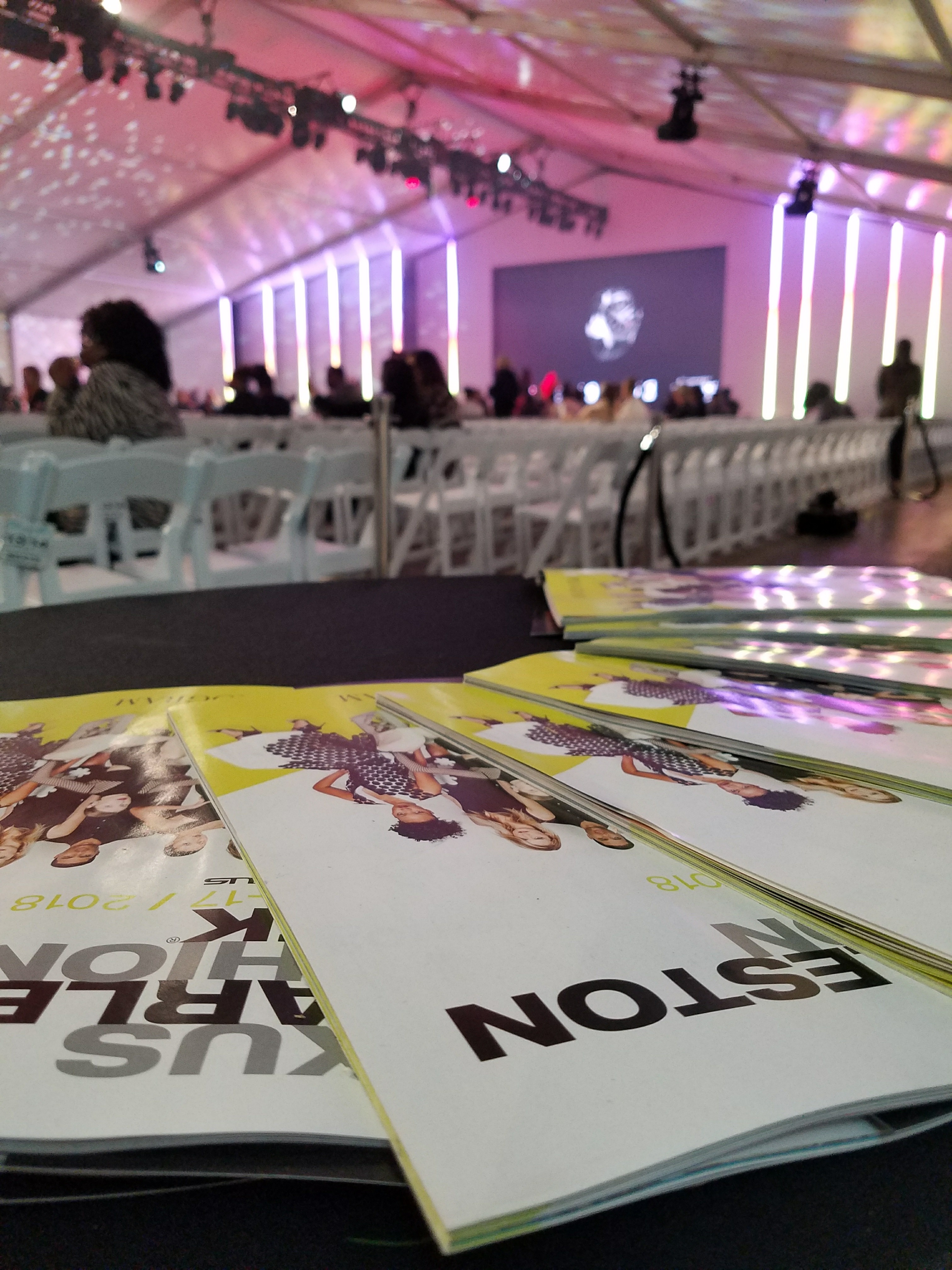 Table with programs spread out and a crowd of seated people in the background