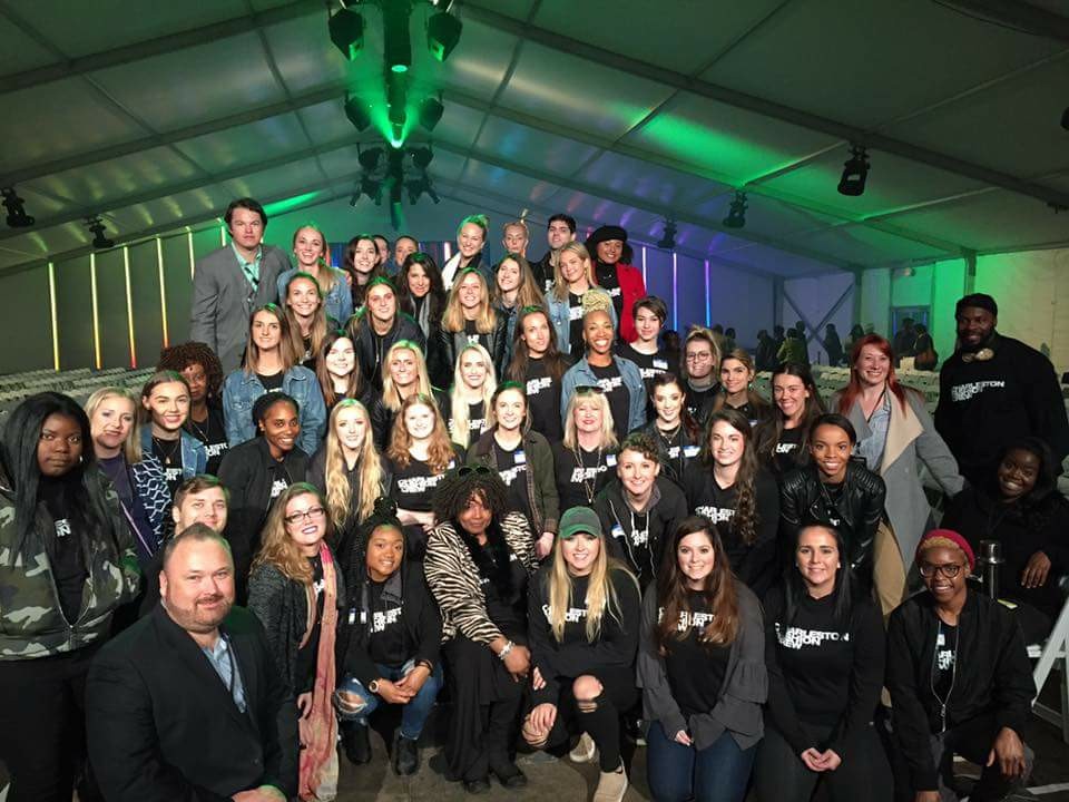 Group shot of a large number of people in an event tent with green lights on the ceiling