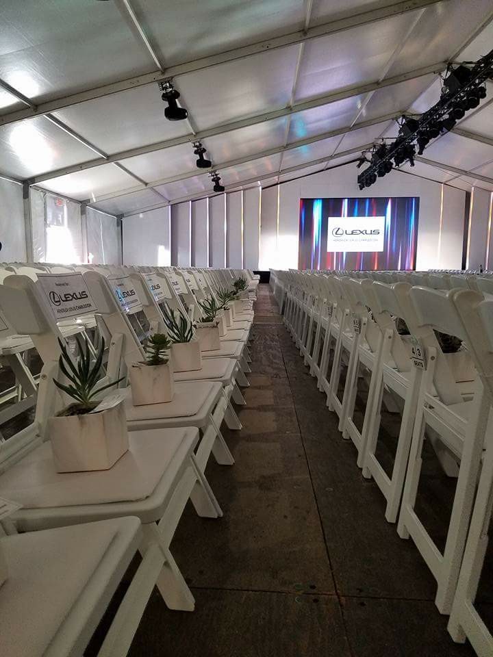 Rows of empty white chairs with a plant on each chair