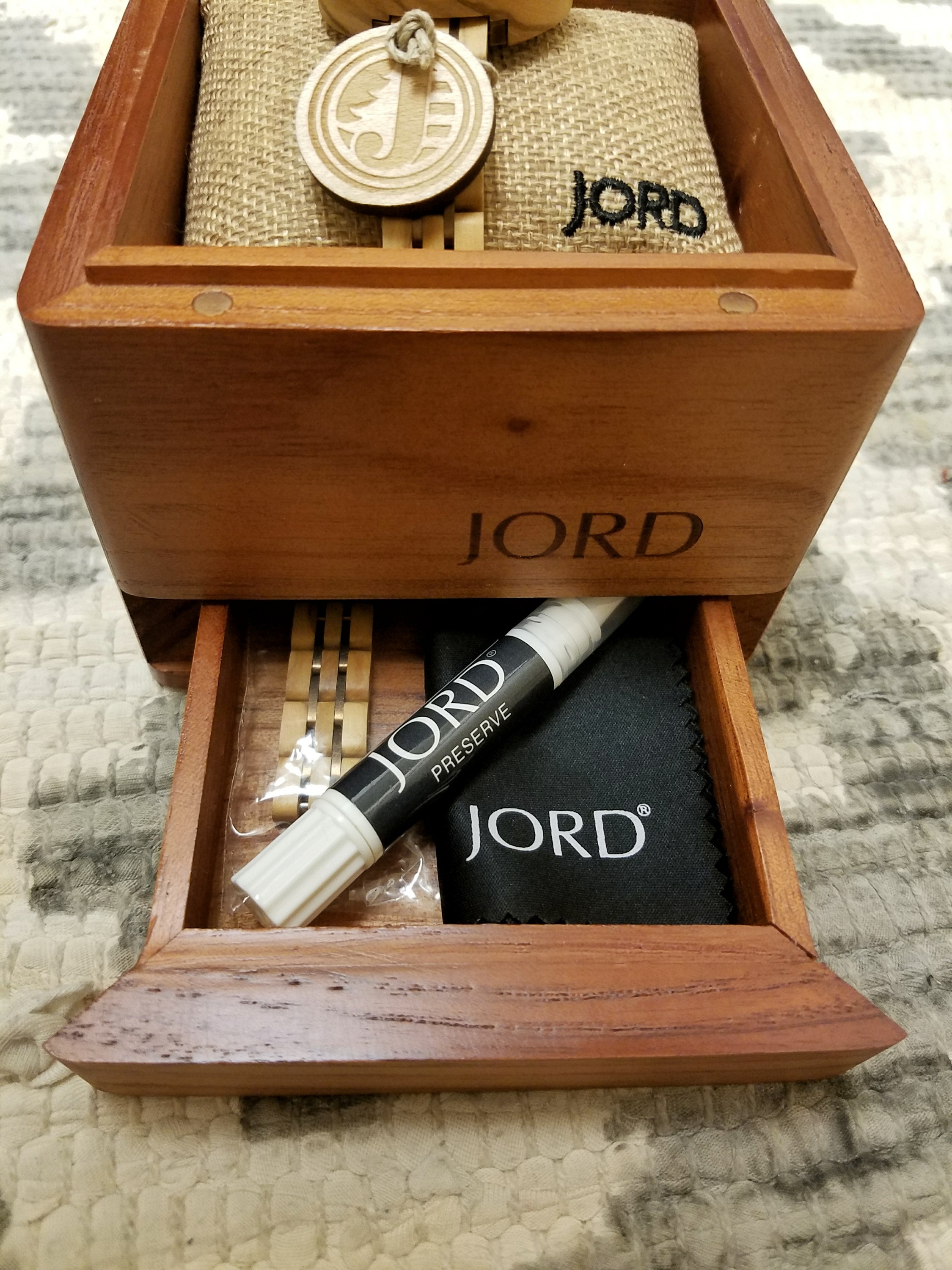 Wooden box with the word JORD and a drawer open with watch accessories