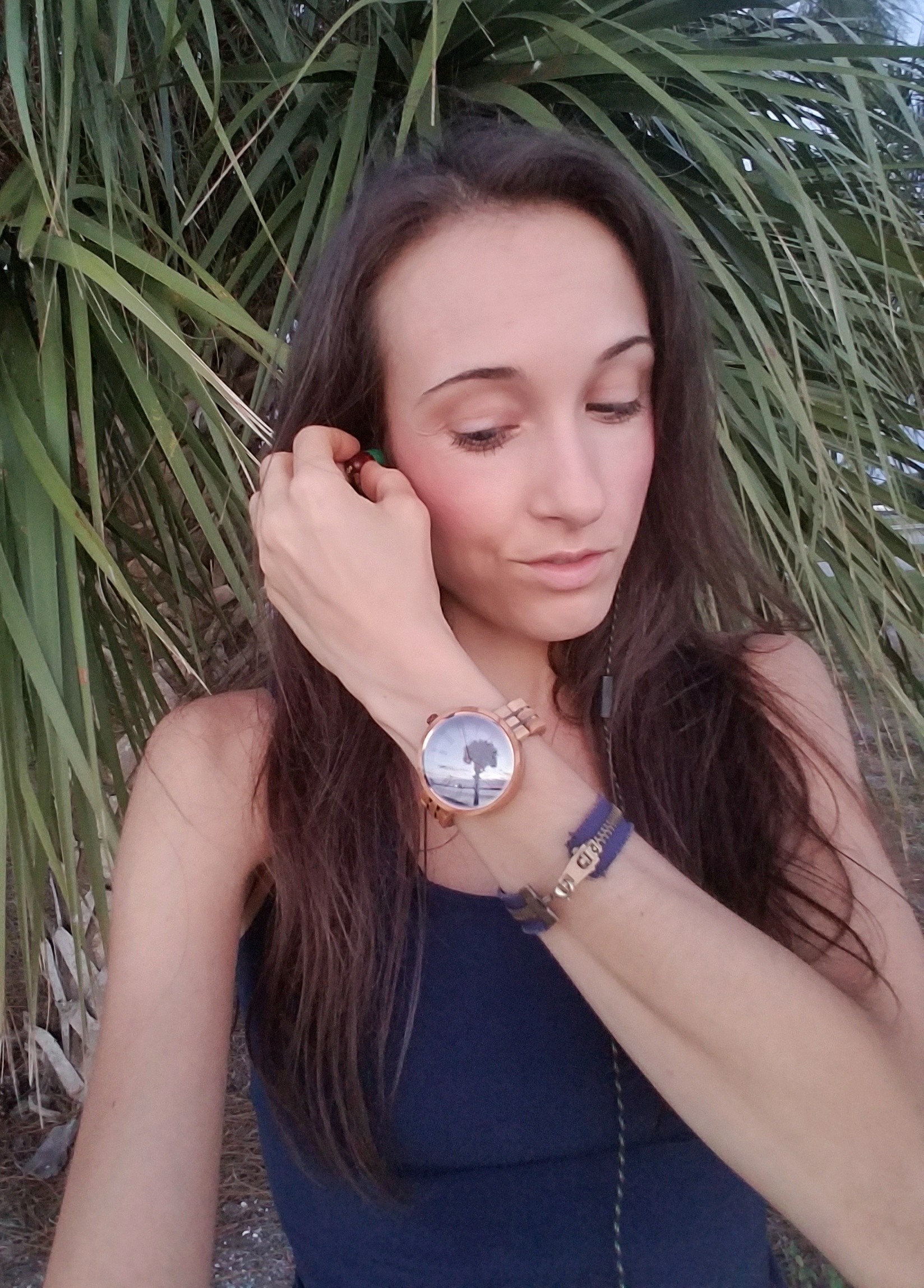 Woman standing in front of a palm tree with a wooden watch