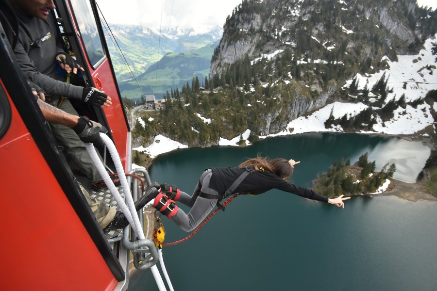 Woman bungee jumping over a lake in the Swiss Alps