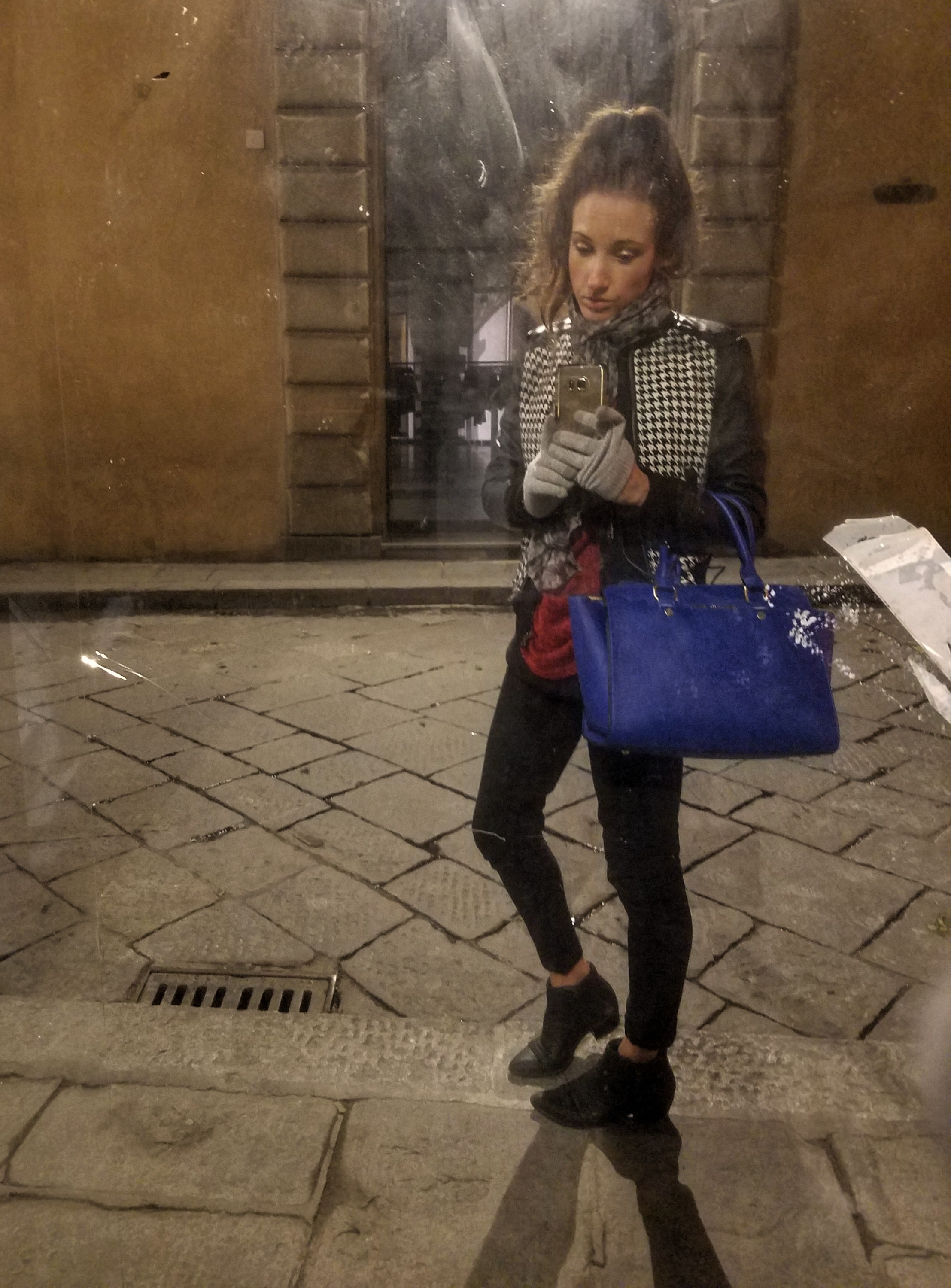 Woman taking a selfie in a mirror on a street