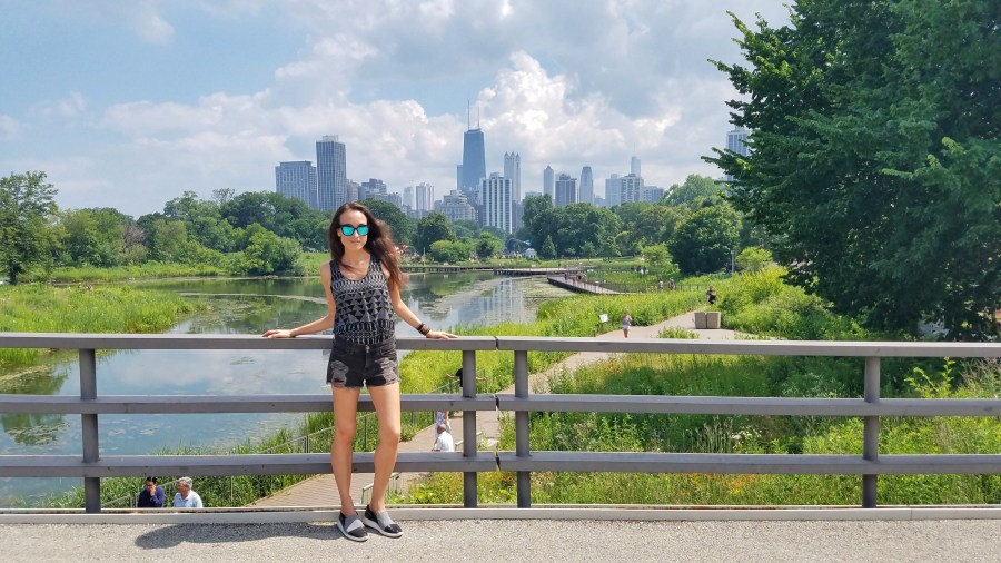 Woman posing near a river with the city of Chicago behind her