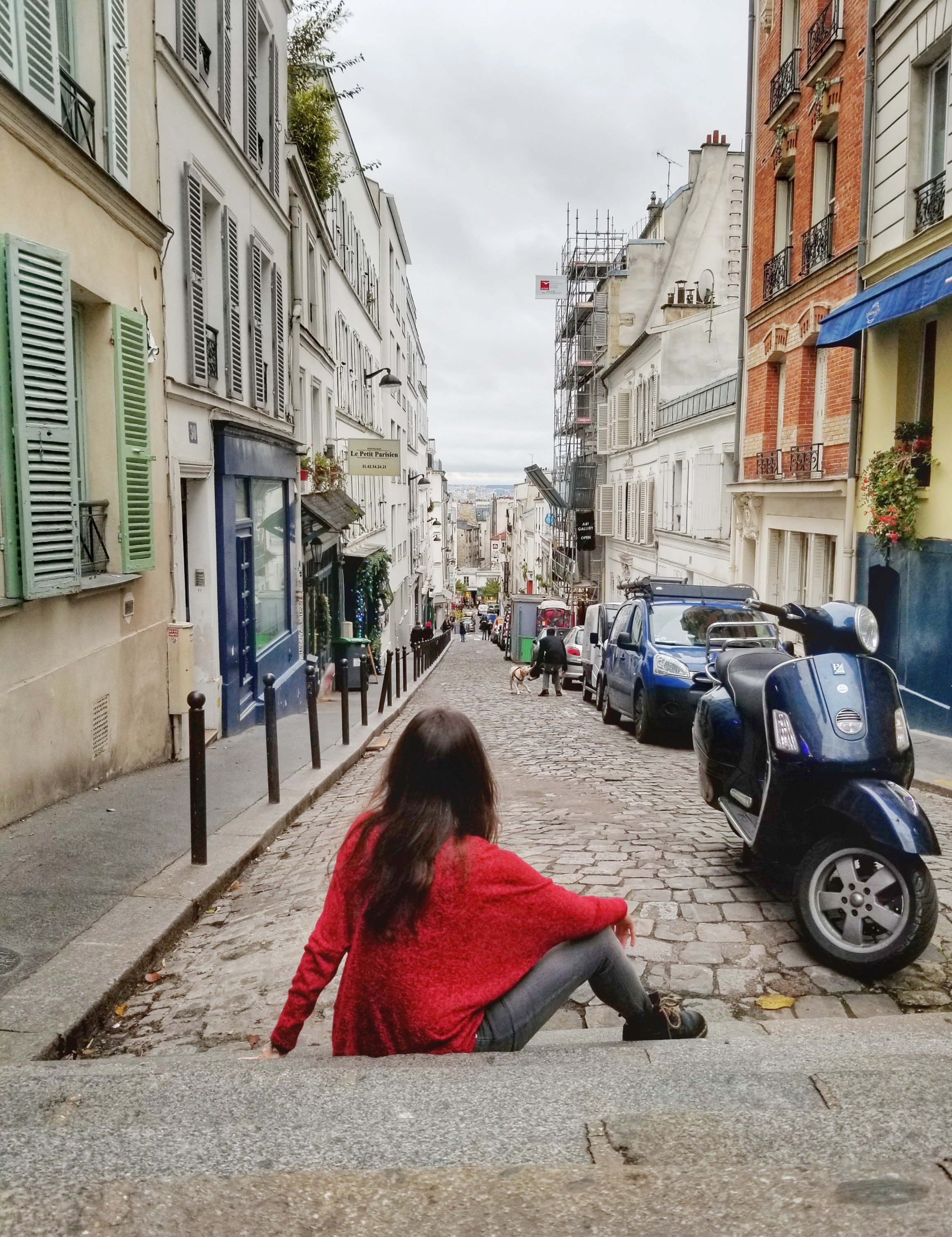 Woman sitting on a cobblestone street in Paris