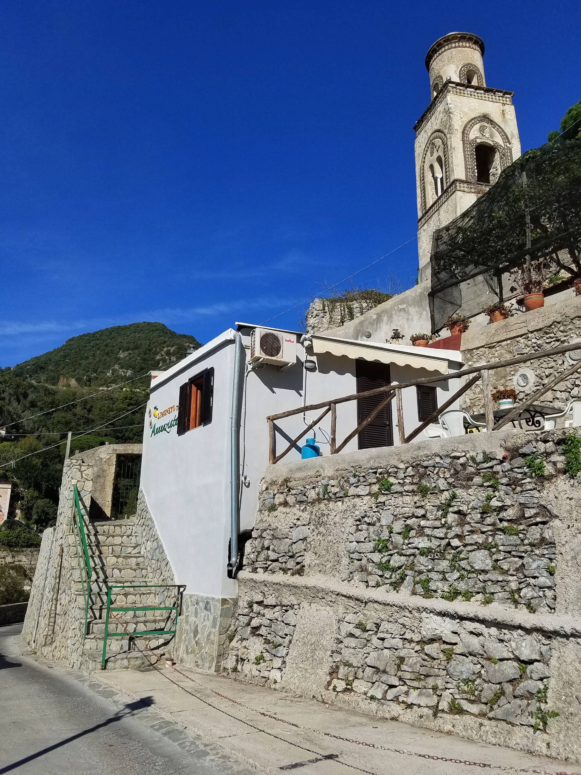 Small white building surrounded by a stone wall and a tower above it