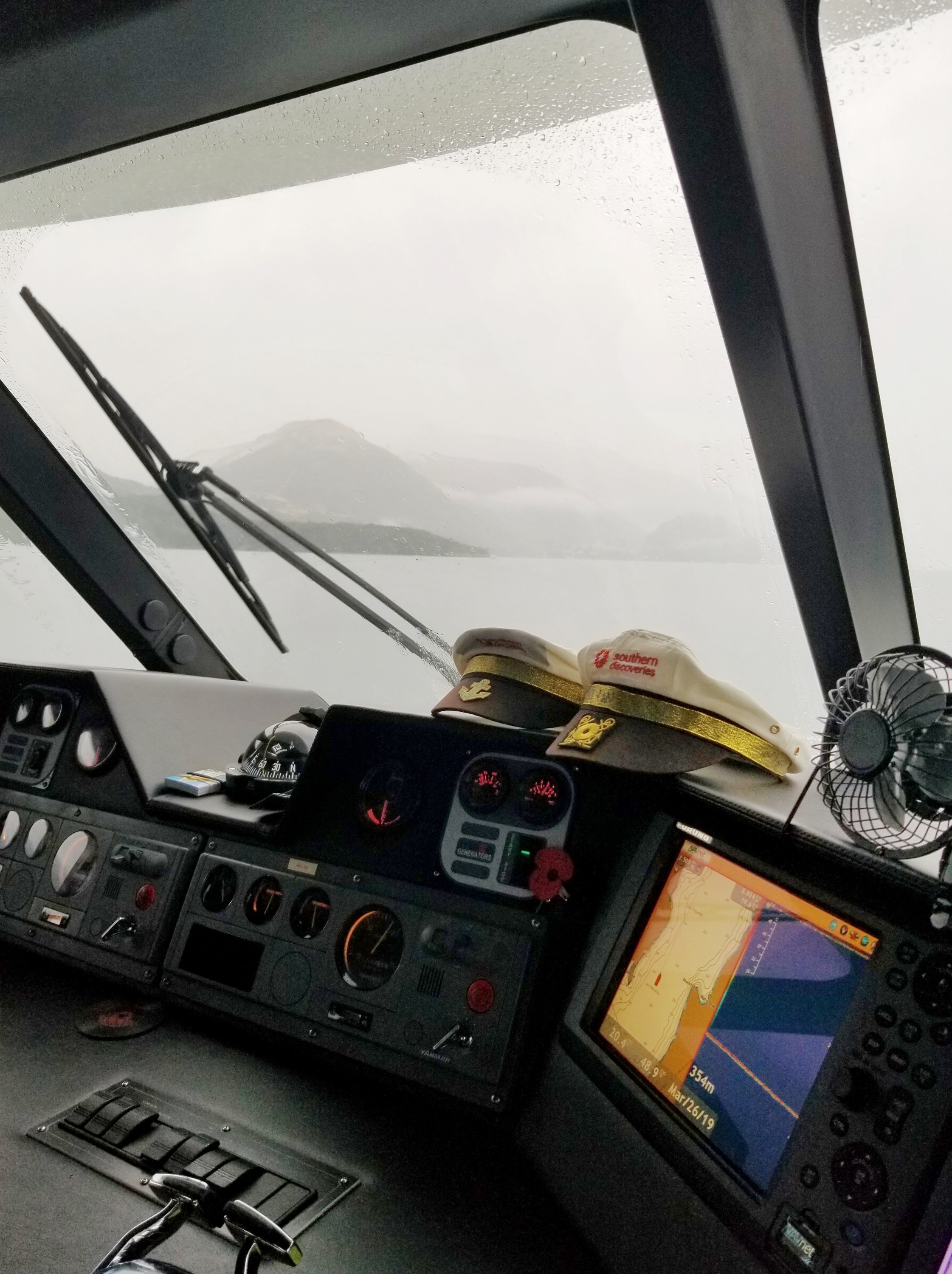 Wheelhouse of a boat with two captains hats on the control panel