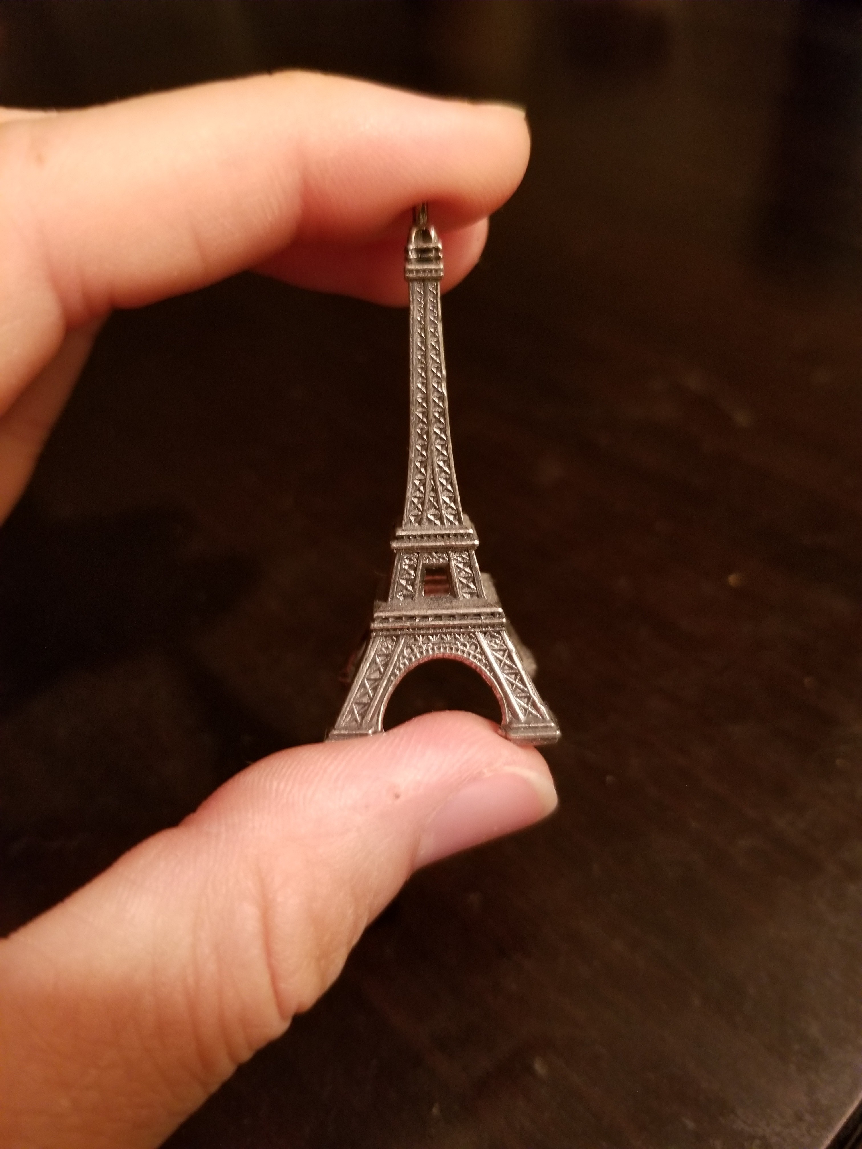 Hand holding mini Eiffel Tower statue