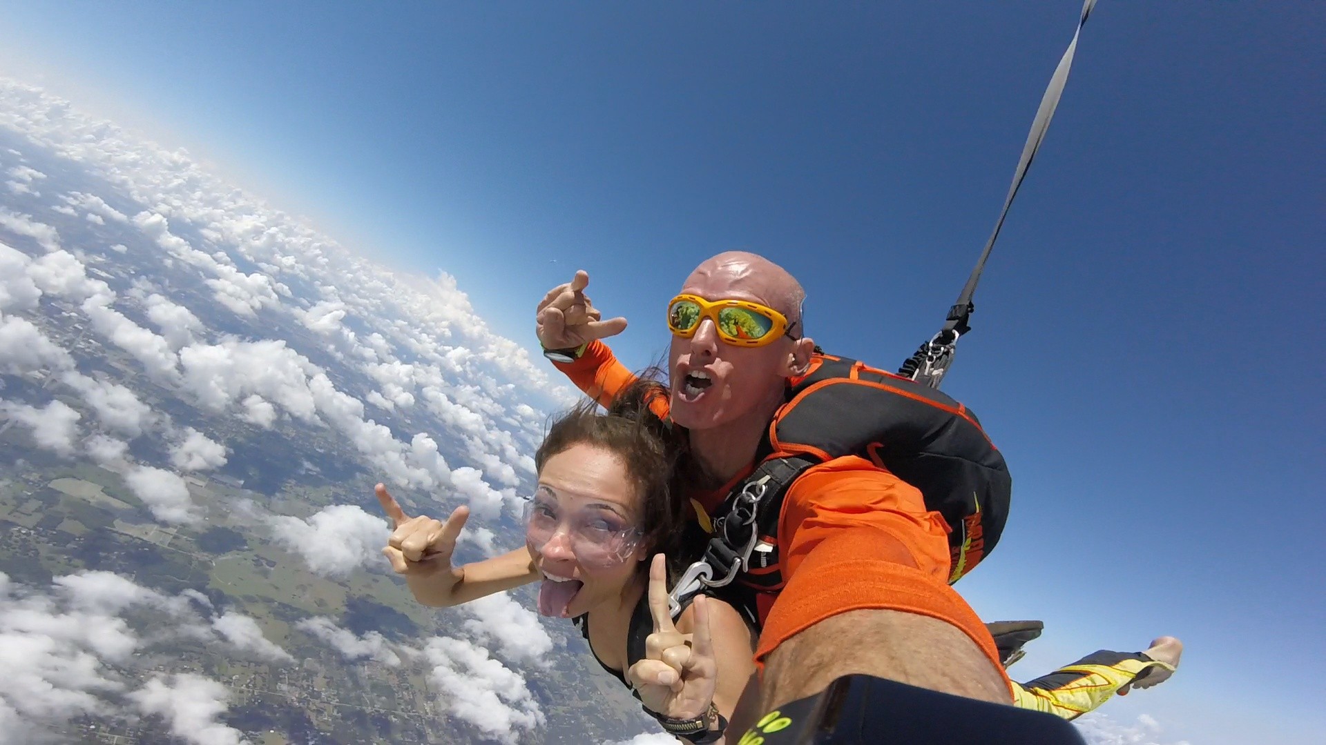 Woman and man tandem skydiving and giving the horns