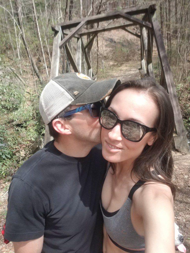 Man kissing woman on the cheek on a hiking trail