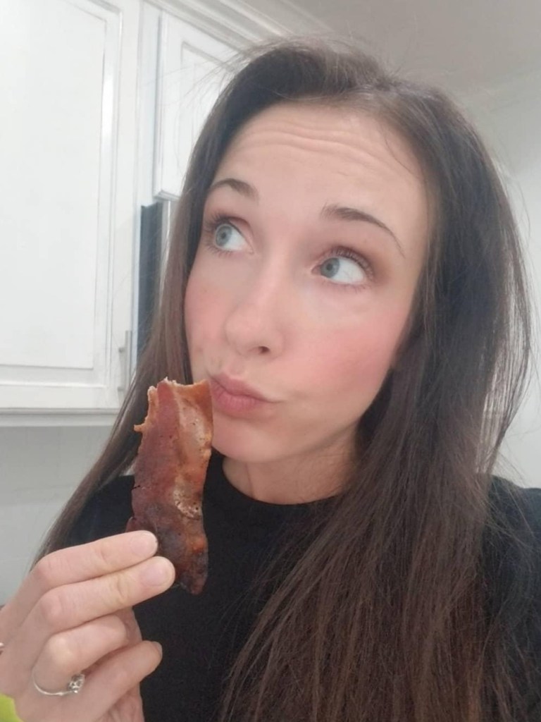 Woman eating a piece of bacon