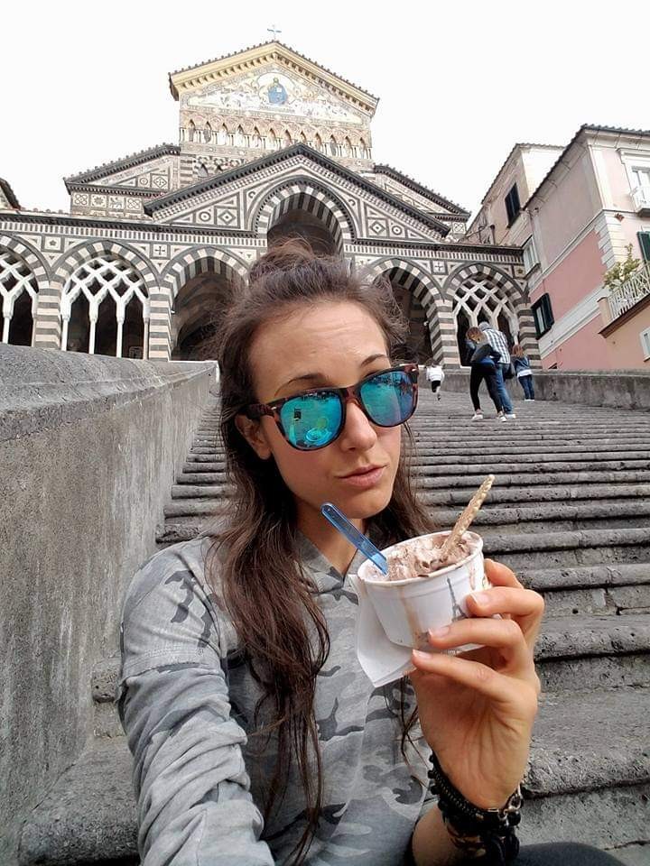 Woman eating a cup of gelato on the steps of a church in Italy
