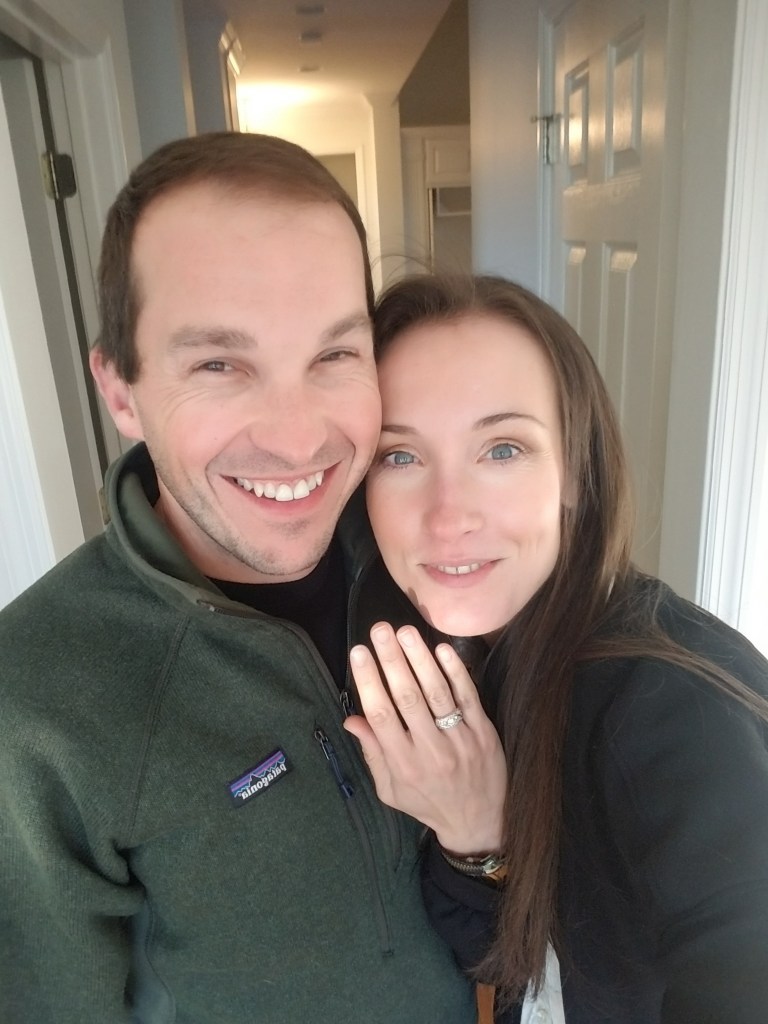 Man and woman smiling with woman wearing an engagement ring