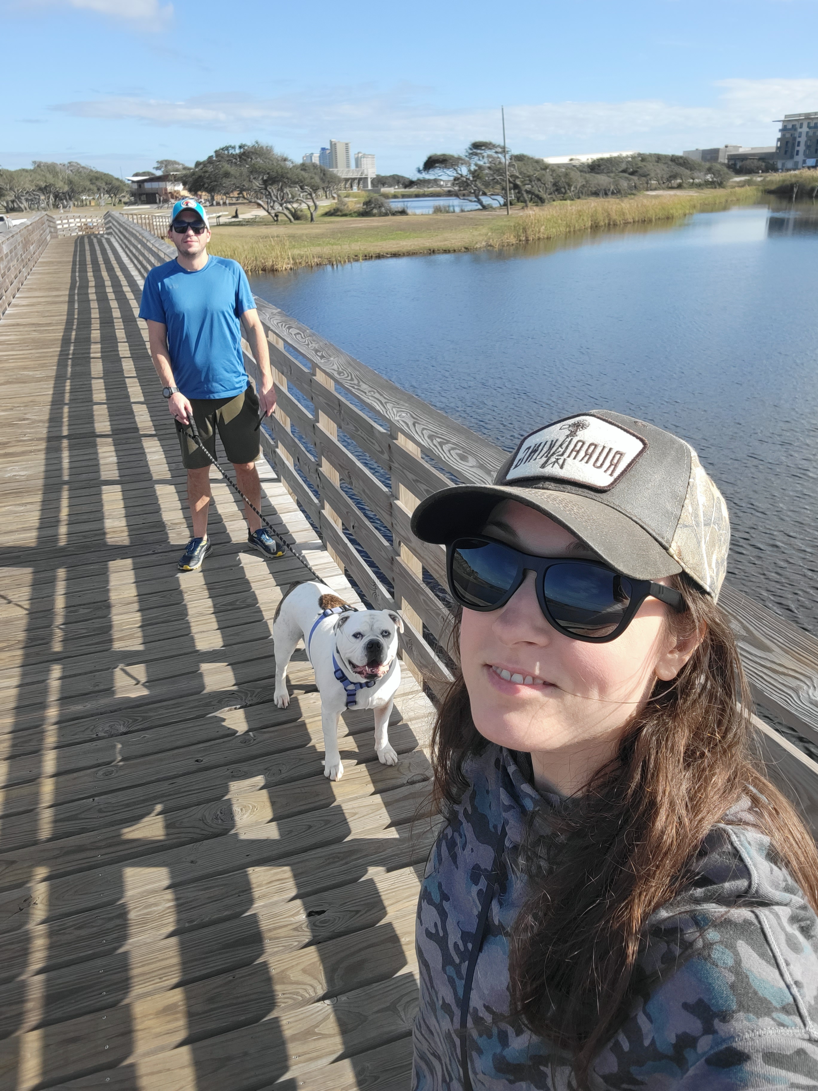 Couple with dog walking along boardwalk at Gulf State Park Alabama
