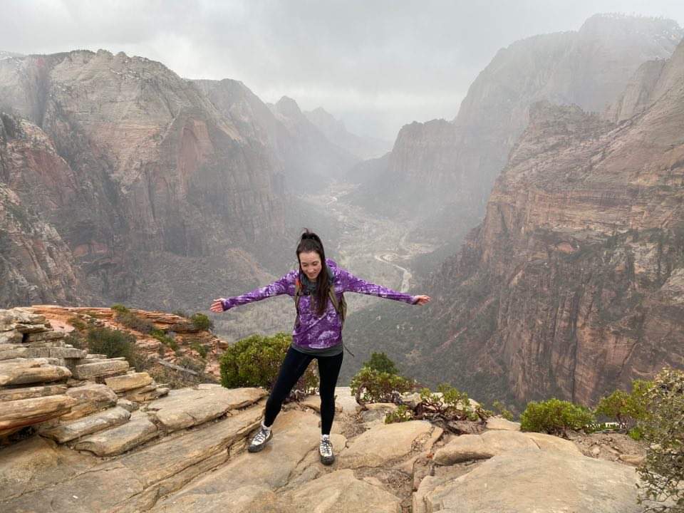 Female hiker with arms outstretched at the top of Angels Landing Zion National Park 