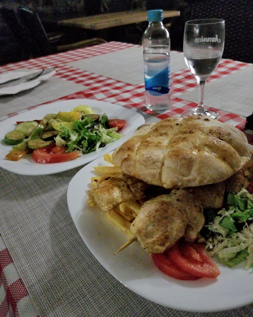 A plate of mixed vegetables and a plate of naan bread with chicken kabobs and French fries