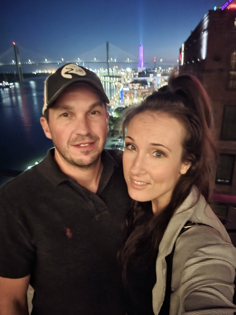 Couple posing with bridge in the background at night