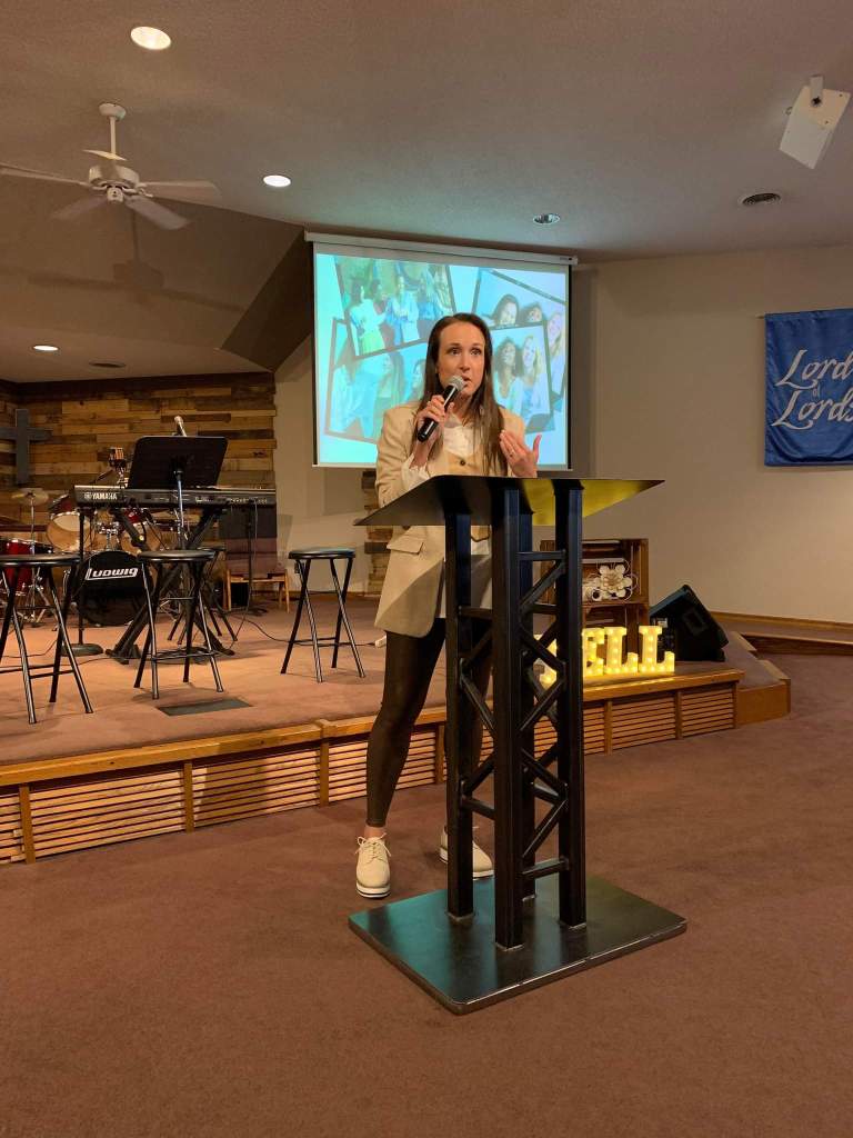 Women standing at a podium and speaking with a microphone in a church setting