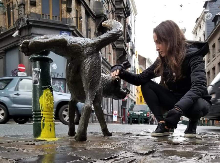 Woman petting a peeing dog statue in Brussels, Belgium