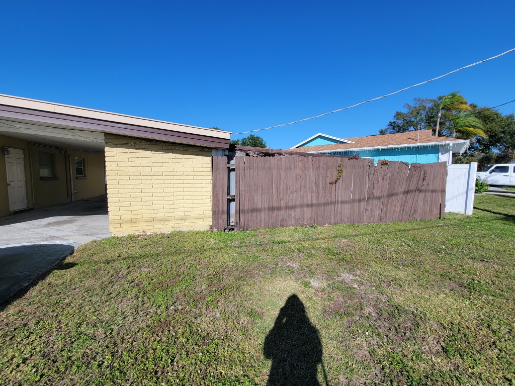 Yellow house exterior with an old brown fence