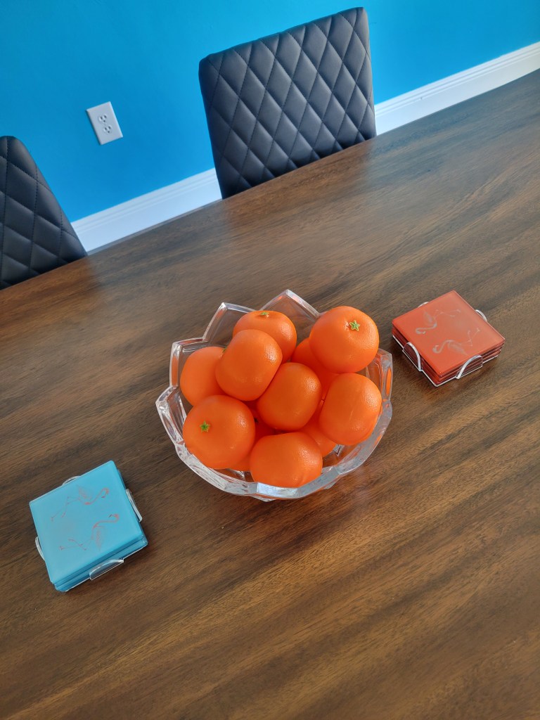 Flamingo coasters next to a bowl of oranges on a table