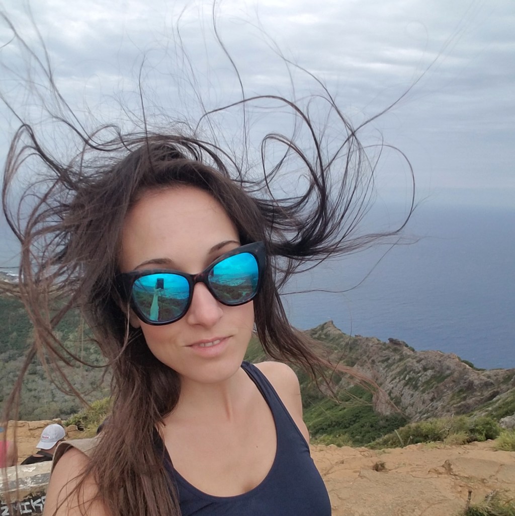 Woman wearing sunglasses with her hair blowing in the air.