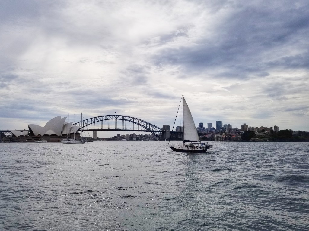 Sydney Harbour with the bridge, opera house, and a sailboat