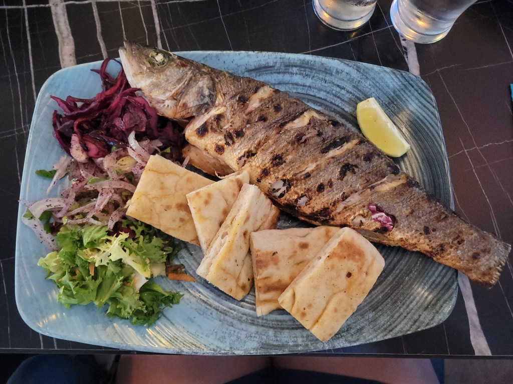Traditional Turkish meal with a whole sea bass, lavash bread, and salad