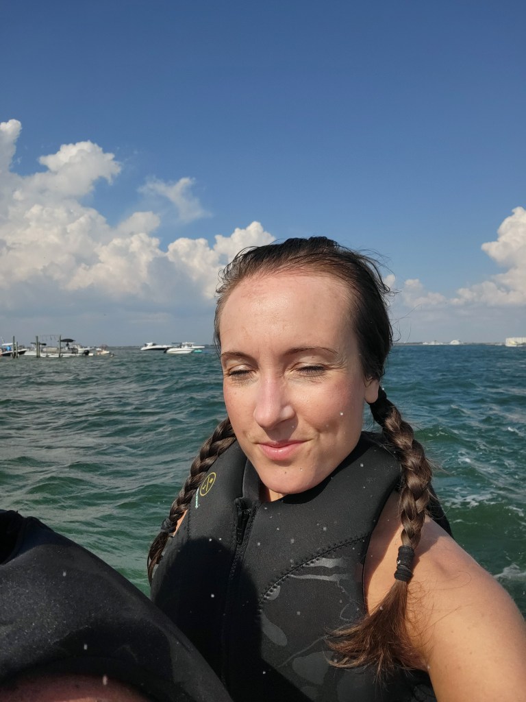 Woman with eyes closed after getting water in her face on a jet ski