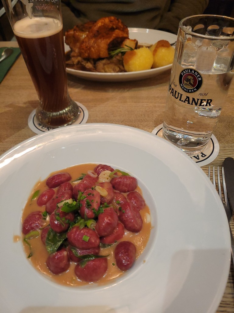 Plate of gnocchi and plate of pork knuckle and potatoes on a restaurant table