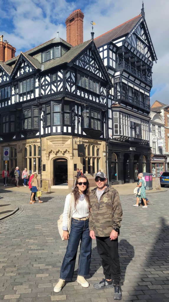 Man and woman posing in front of a Tudor building in the UK