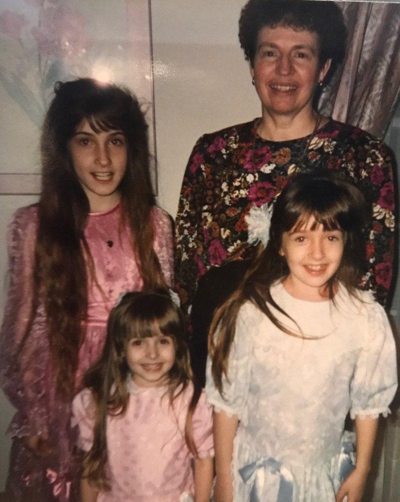 1990s family photo of a grandmother and three granddaughters, all wearing dresses