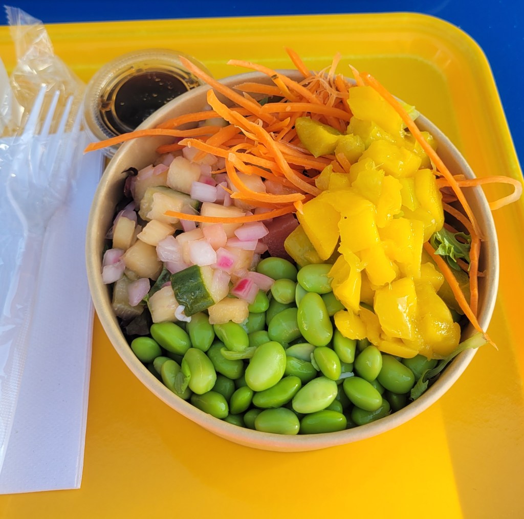 Poke bowl on a yellow tray with a plastic fork