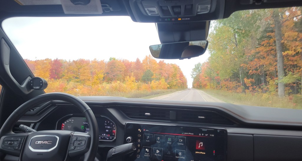 Fall leaf color seen out of a windshield of a vehicle driving down a rural road