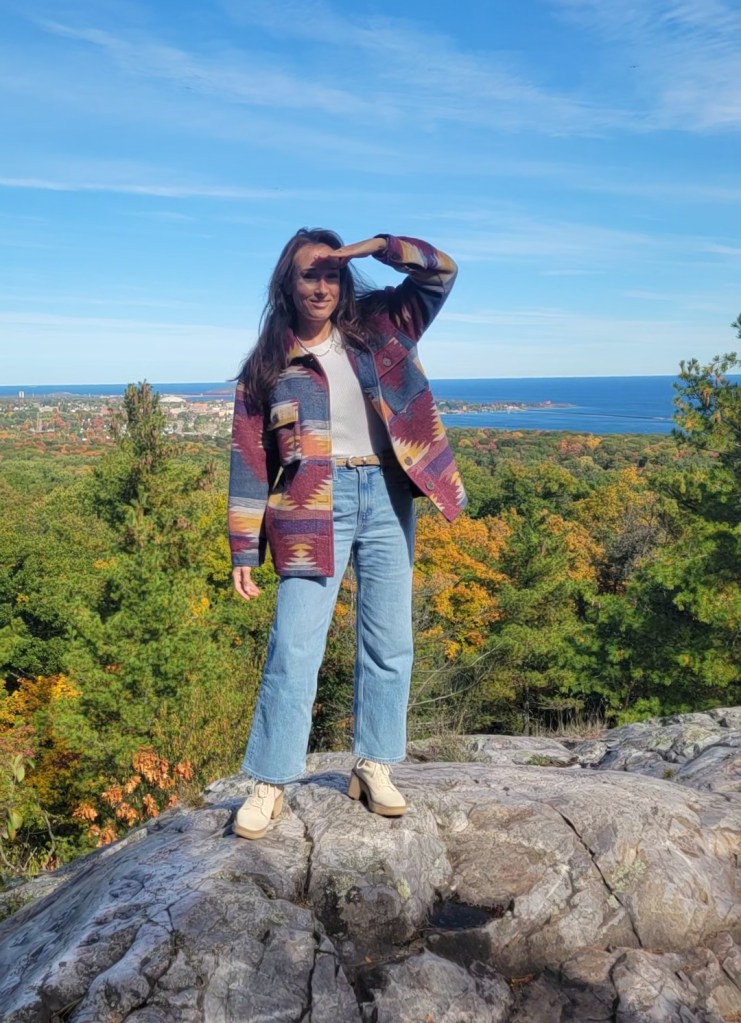 Woman standing on a rocky ledge overlooking a town