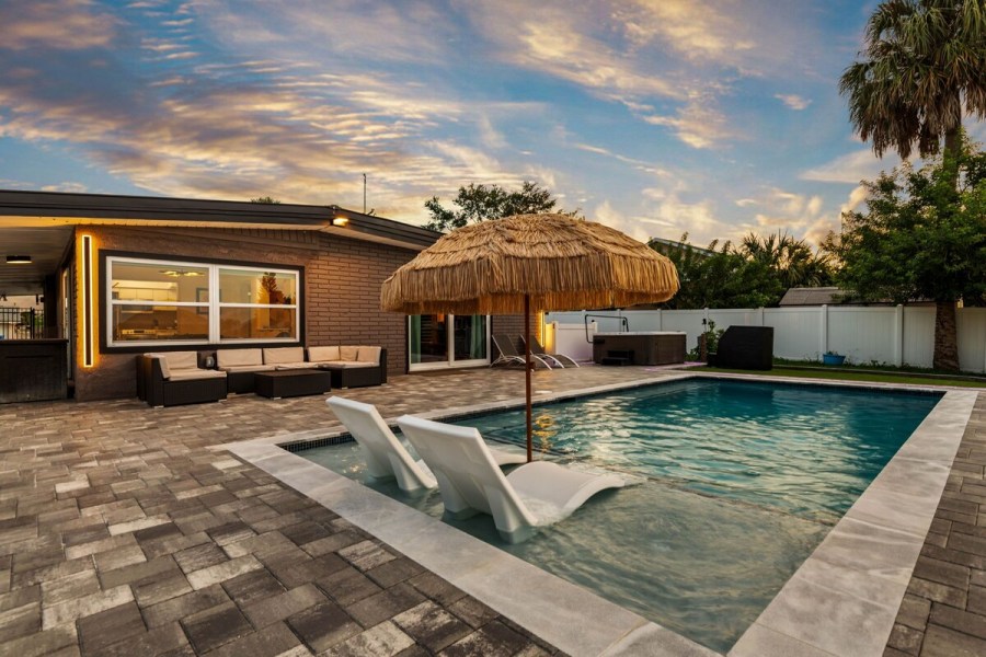 Backyard pool with lounge chairs and tiki umbrella