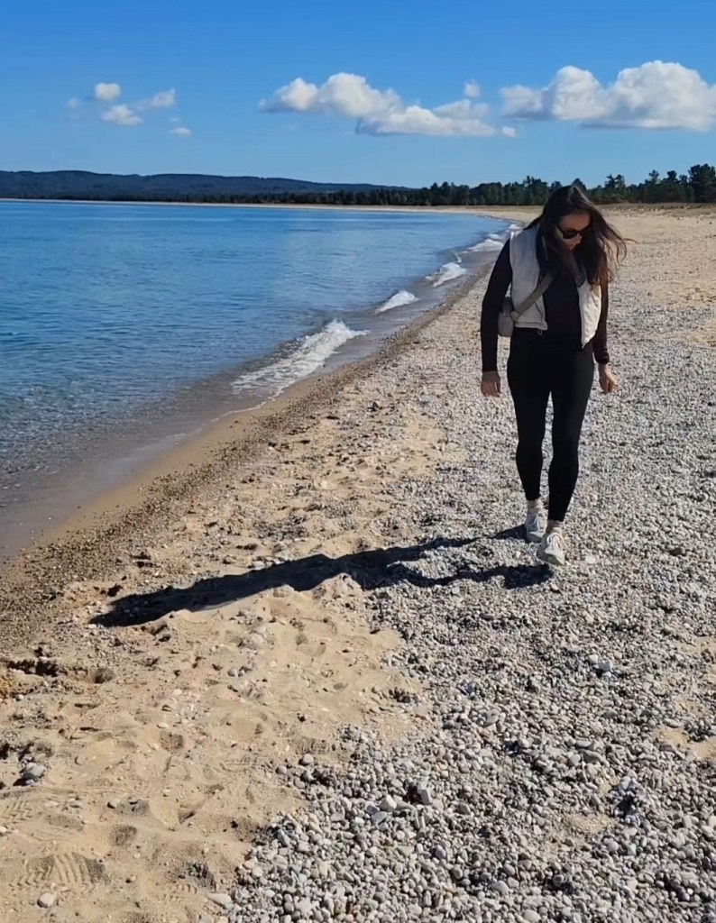 Woman in activewear walking on a remote beach in Michigan 